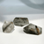 Three highly polished, irregularly shaped Garden Quartz gemstones. The quartz is clear to smoky, with prominent internal deposits of brown and black minerals resembling a small, earthy landscape.