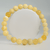 Orange Calcite Gemstone Bracelet made with polished round natural calcite beads displayed in a circular shape on a white background.