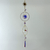 Hanging sun catcher with a sun-shaped metal charm, purple stones, circular and oval frames, and faceted reflective crystals.