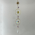 Hanging sun catcher with a gold sunburst, purple crystals, circular rings, reflective faceted spheres, and a clear teardrop prism.