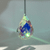 Faceted teardrop crystal sun catcher hanging from a black cord, casting colorful blue, green, and purple reflections.