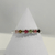 Multicolor Tourmaline eternity ring featuring pink, green, blue, and purple gemstones set in a delicate band on a white jewelry stand.