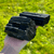Rough black tourmaline crystals held in a hand outdoors, showcasing their dark color and natural texture.