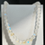 Aura Necklace featuring iridescent round beads with soft pastel blue, yellow, and rainbow reflections, displayed hanging against a light background.