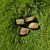 Four rough tiger eye stones with natural brown and golden bands resting on green grass.