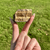 Close-up of a rough tiger eye stone held between two fingers, showing its natural golden-brown bands.