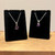 Two rough amethyst necklaces on black velvet stands, featuring silver chains and distinct purple stone pendants.