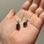 Hand holding two rough amethyst necklaces, featuring textured purple pendants attached to silver chains.