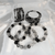 A collection of polished Black Rutile Quartz Gemstone Bracelets arranged on a soft white fabric, highlighting the different bead size options.