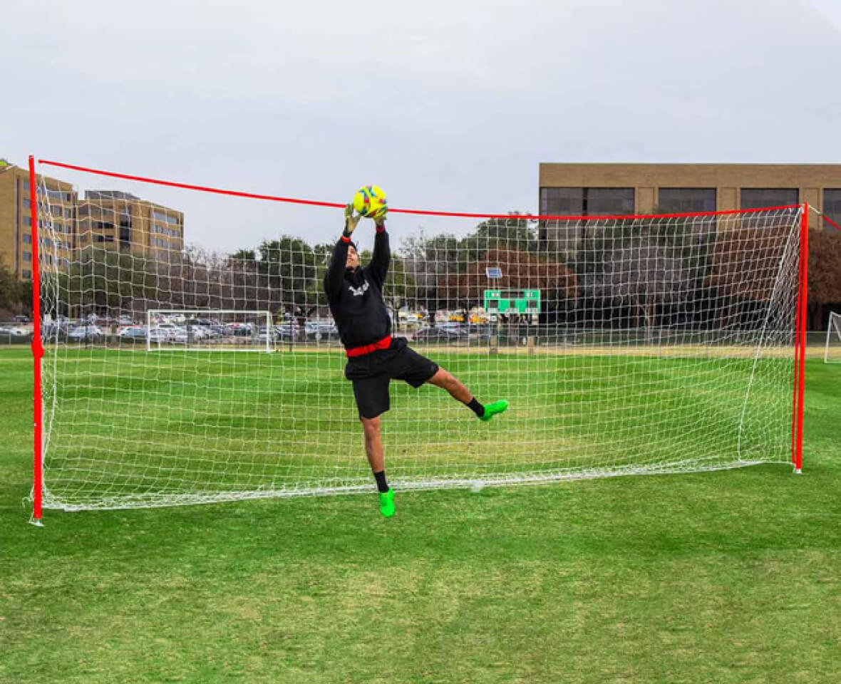 Goalkeeper making a save in front of a soccer goal.