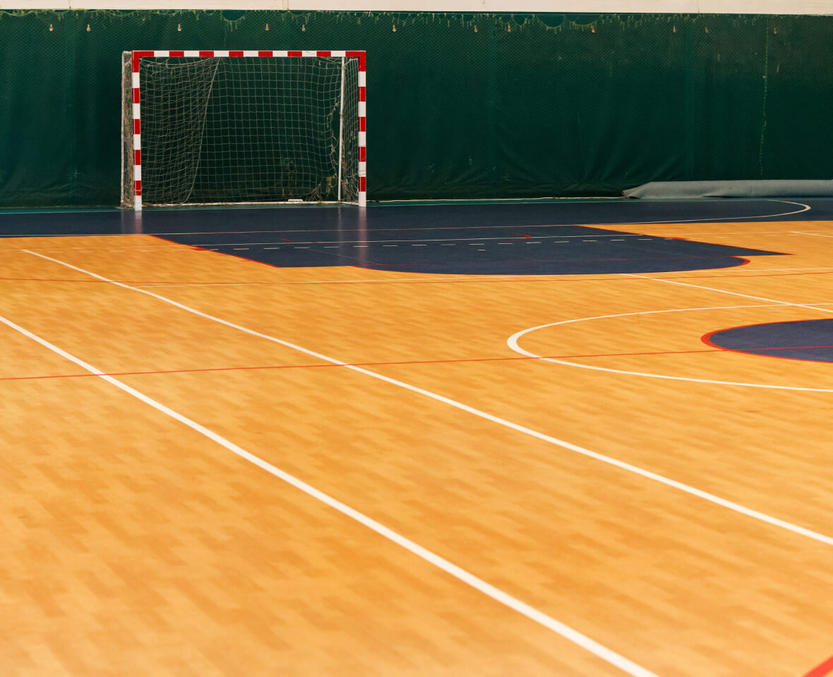 Indoor futsal match with players shooting at a regulation futsal goal