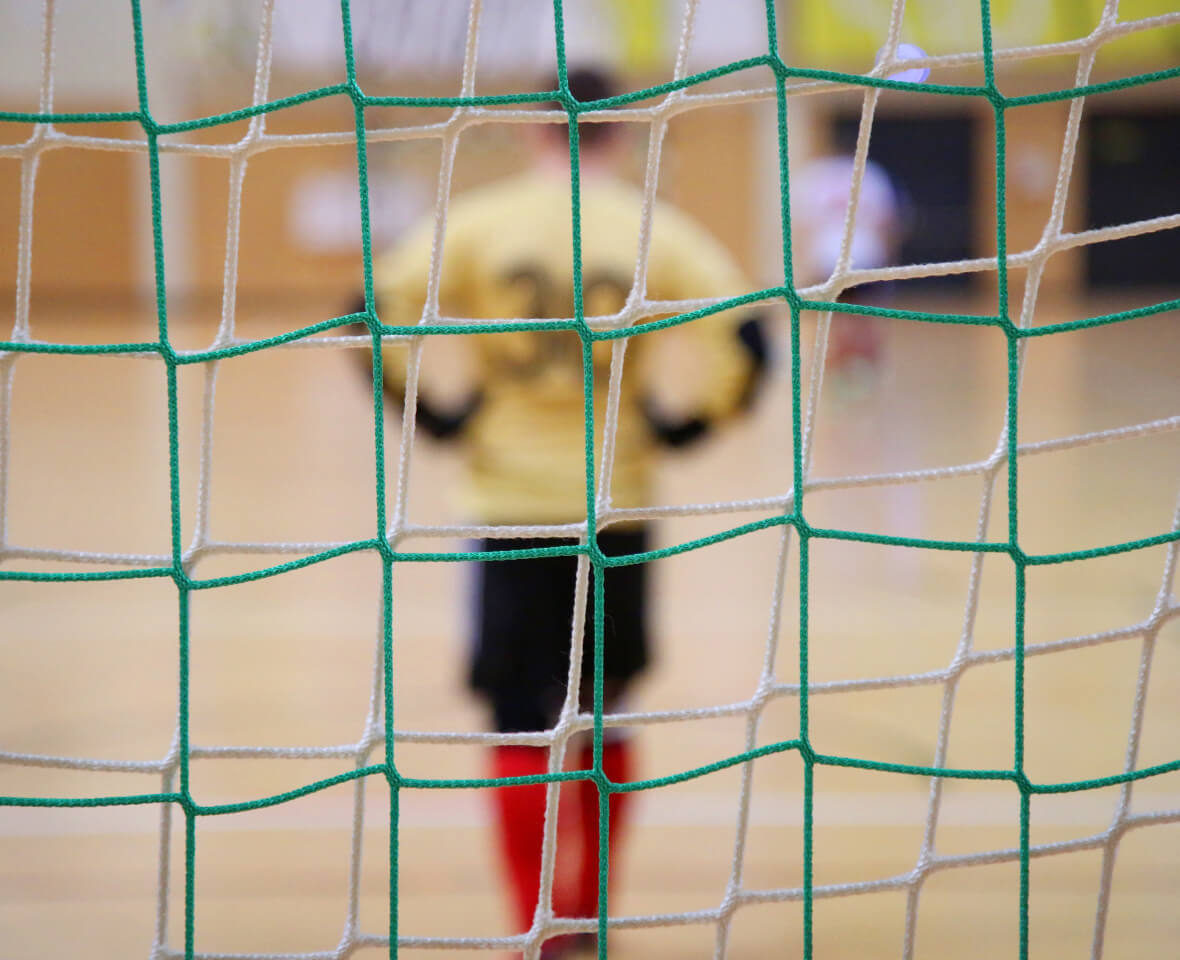 Player shooting at a futsal goal during indoor practice