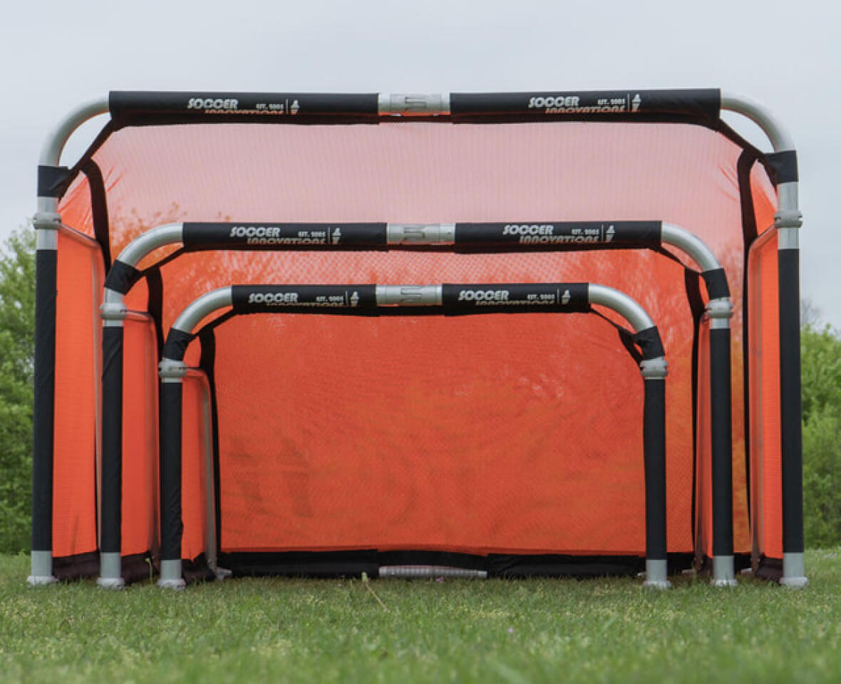 Set of orange pop-up soccer goals on grass.