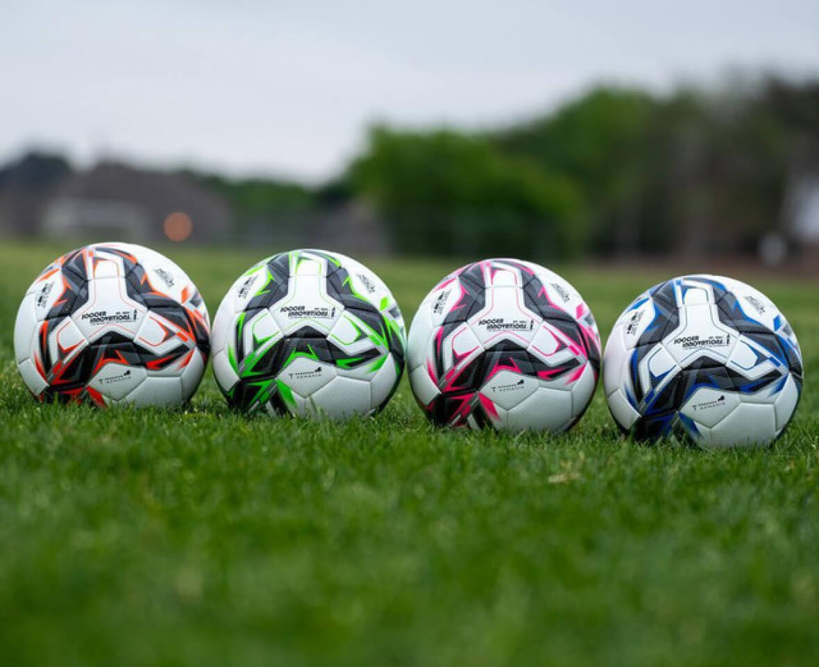 Four colorful soccer balls lined up on a field.