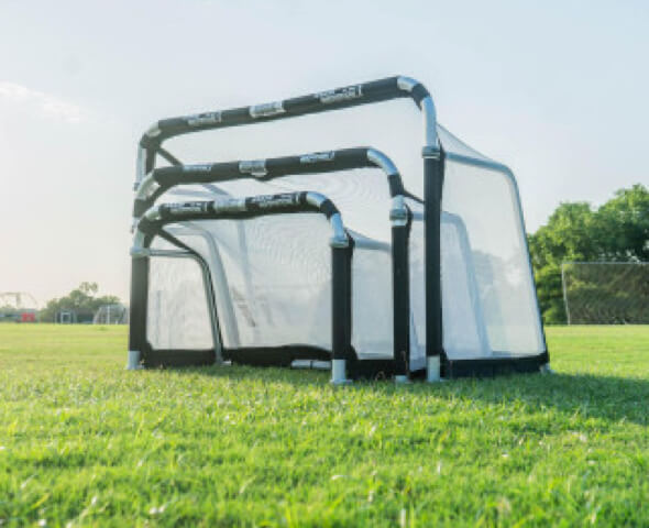 Portable pop-up soccer coaching goals nested together on a grass field
