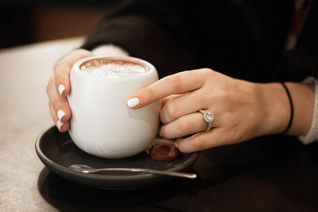 woman with diamond ring holding hot chocolate