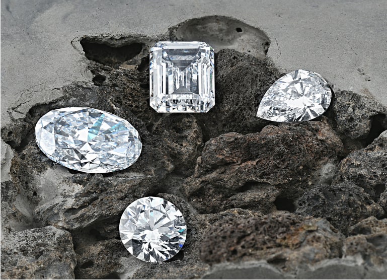 Four diamonds of various shapes on a rocky surface