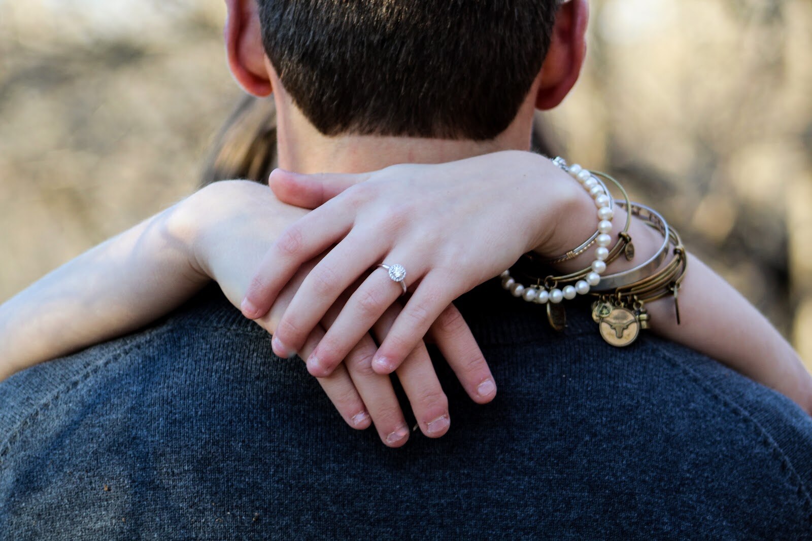 woman's hands around back of man's neck displaying engagement ring woman's hands around back of man's neck displaying engagement ring