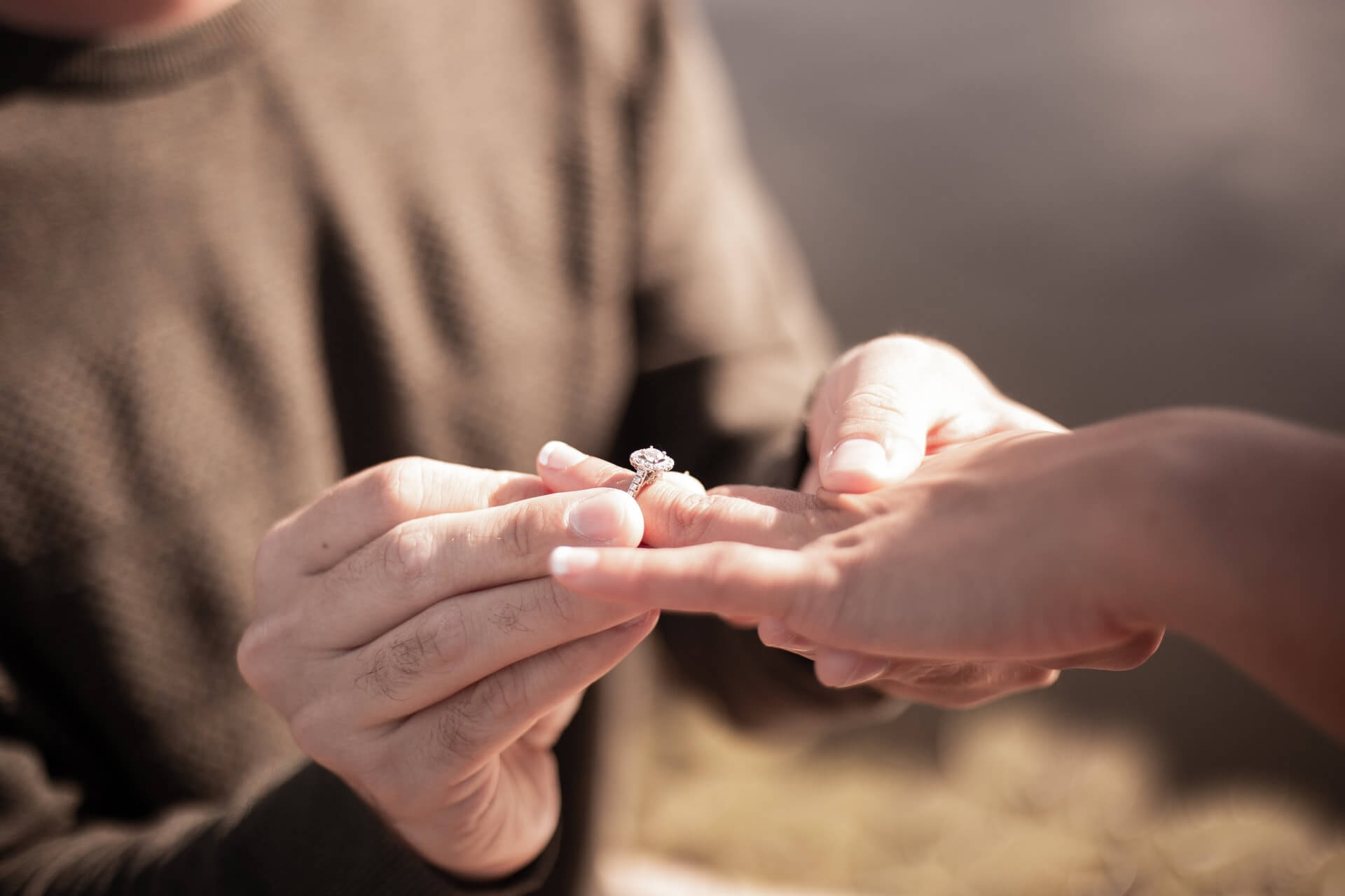 man placing an engagement ring on a woman’s finger