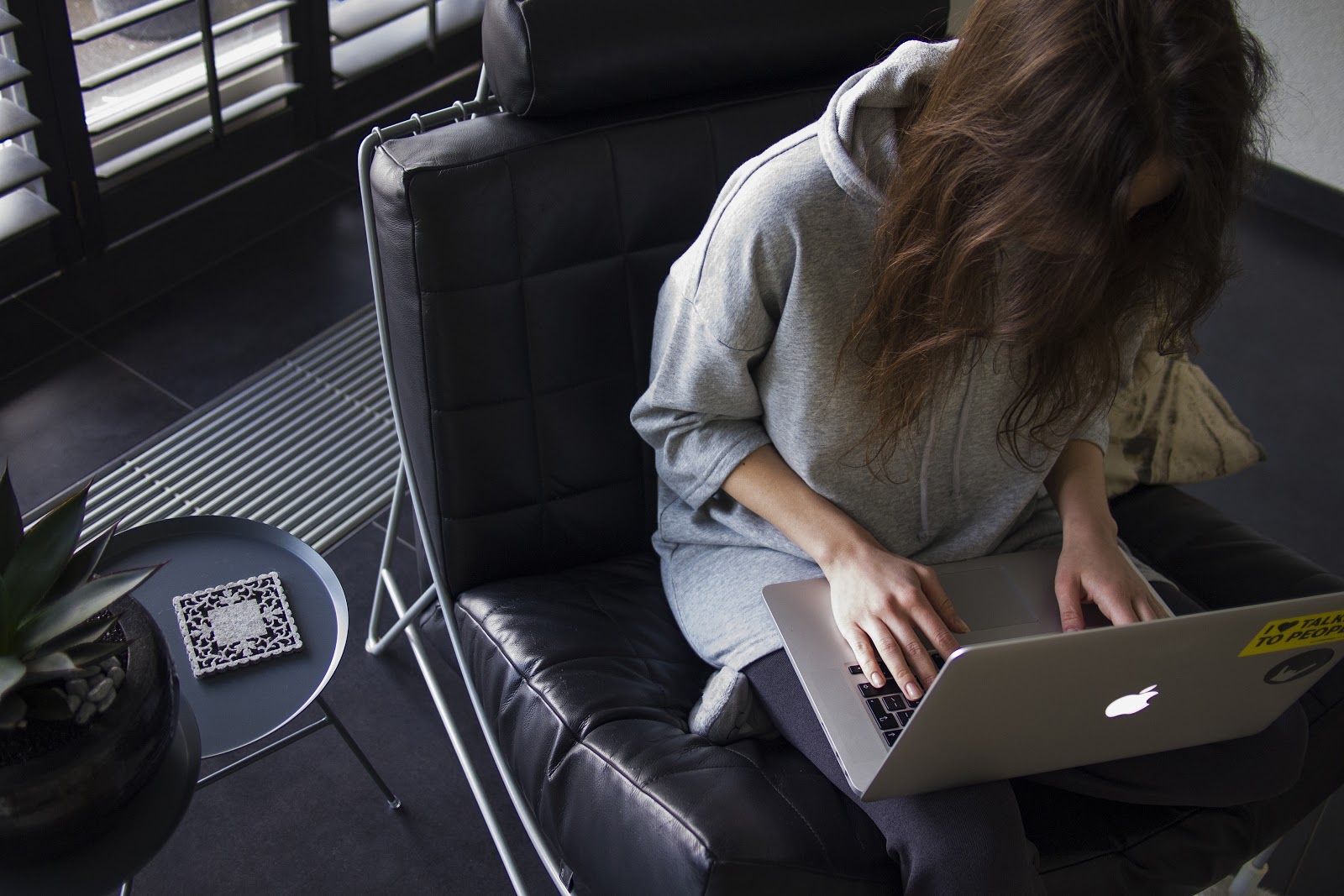 young woman in leather chair bent over laptop working young woman in leather chair bent over laptop working