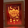 An Islamic art painting of Ramadan in a wooden frame, illuminated with Red lighting that runs on a battery