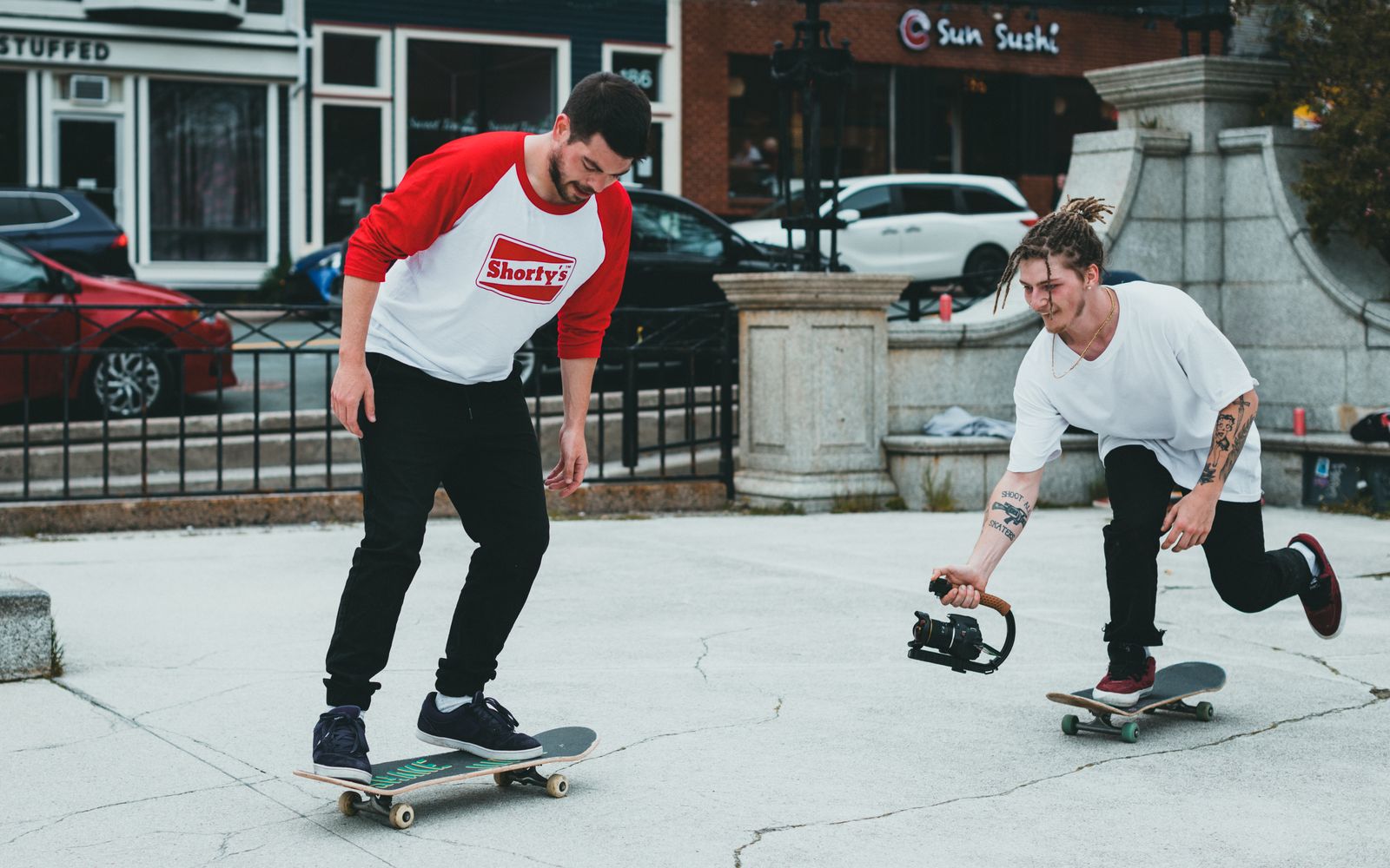 An operator carrying a camera on a low top-handle grip, chasing a skater at deck height.