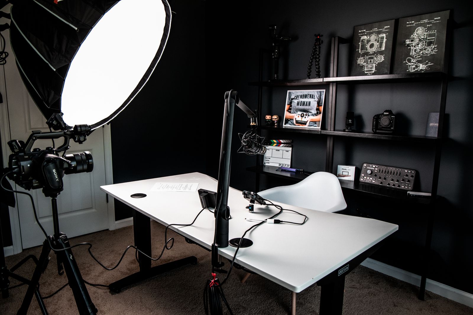 A single-presenter room assembled from separate pieces — a softbox light on a
                                  stand, a camera on a tripod behind it, and a microphone on a boom arm reaching
                                  over an empty desk.