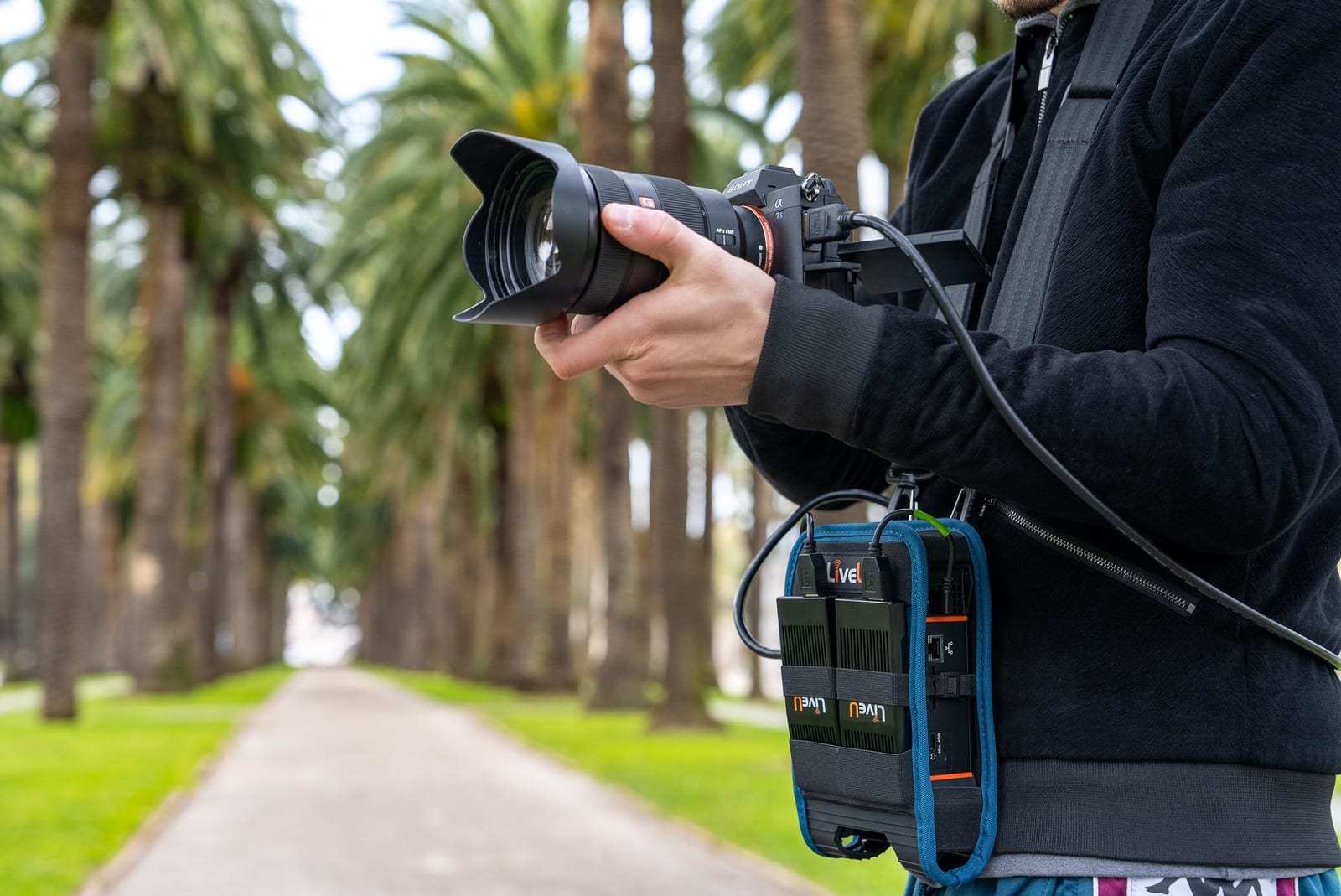 A solo operator filming on the move with a LiveU Solo PRO clipped to their camera rig