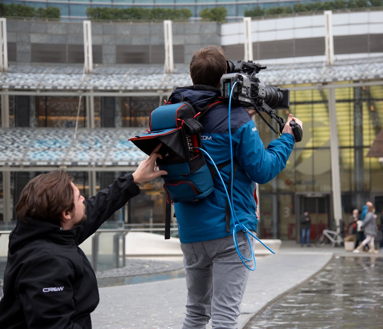 A broadcast crew going live outside with a LiveU backpack unit powering a shoulder-mount camera