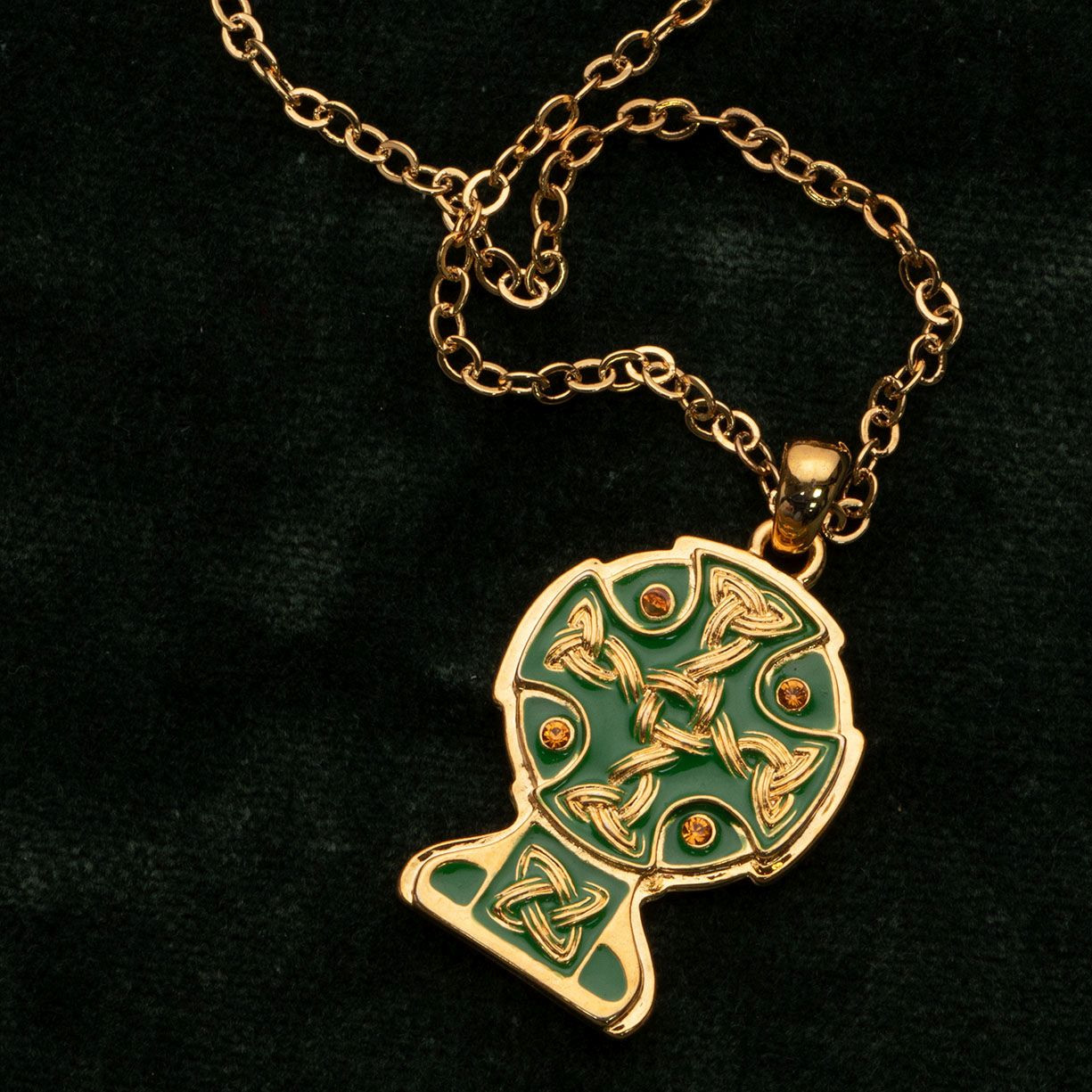 gold Celtic Cross pendant with green enamel accents hangs from an adjustable gold chain with a lobster claw clasp