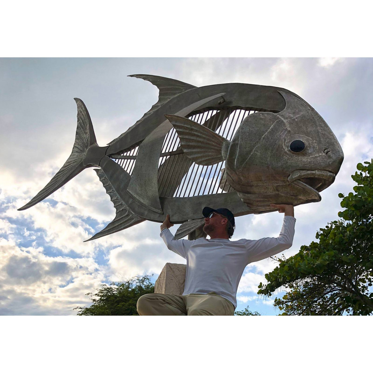 Angler holding a large metal permit sculpture overhead