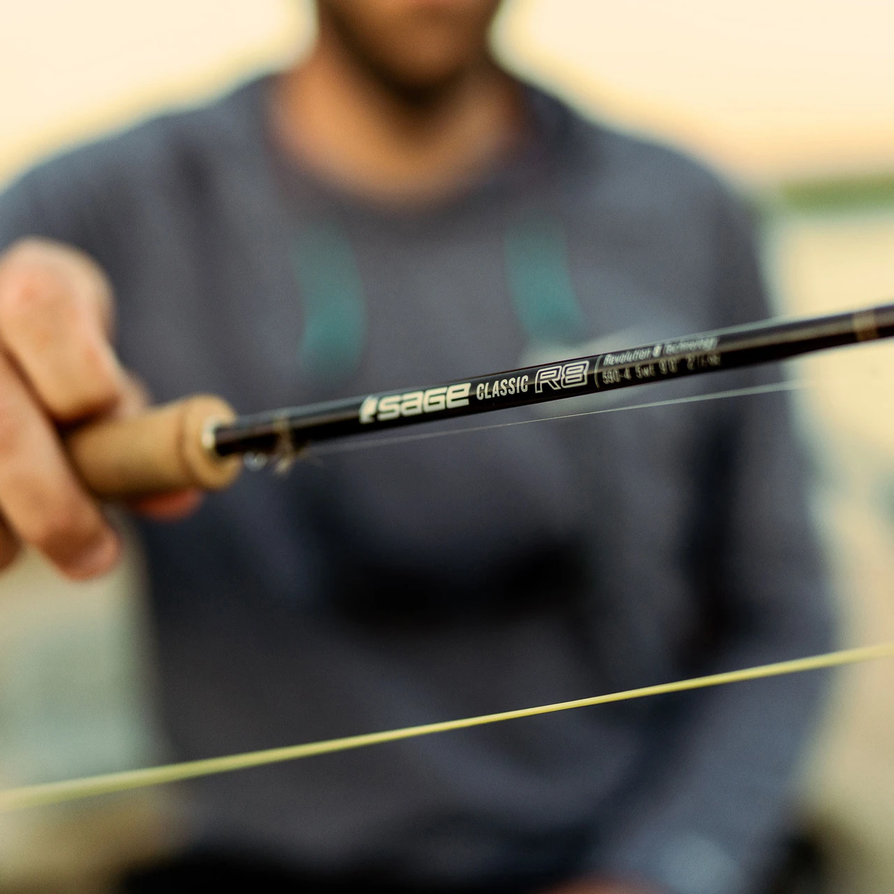 Angler holding a Sage Classic R8 fly rod at the water
