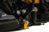 Thrashin Supply Co. carbon-fiber skid plate with gold brackets installed beneath a touring motorcycle