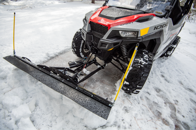 Front view of a UTV with an Open Trail straight plow blade and yellow markers in snow