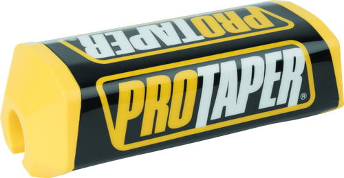 A high-resolution studio product photograph of a ProTaper 2.0 Square Bar Pad in Yellow/Black, set against a clean white background. Displayed at a front-three-quarter angle, the high-density molded closed-cell foam pad features a vibrant yellow vinyl cover with bold black "PROTAPER" block logo graphics printed across the front, black side accents, and a streamlined square profile with cutouts designed specifically for oversized 1-1/8" un-braced handlebars.
