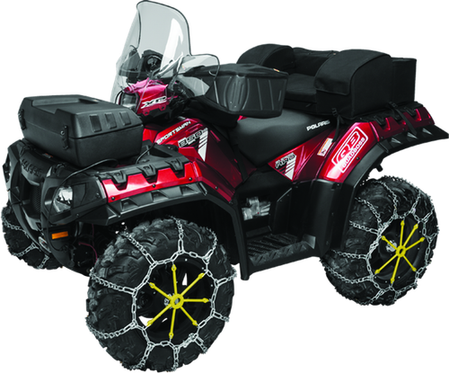 A high-resolution studio product photograph of QuadBoss XL V-Bar Tire Chains mounted tightly around an aggressive black ATV/UTV tread tire, set against a clean white background. Displayed at a front-three-quarter angle, the heavy-duty galvanized steel chain harness wraps securely across the tire's outer tread and sidewall, highlighting the sharp V-bar studs designed for maximum ice and snow traction. The blue plastic QuadBoss storage case sits neatly alongside the mounted tire assembly.