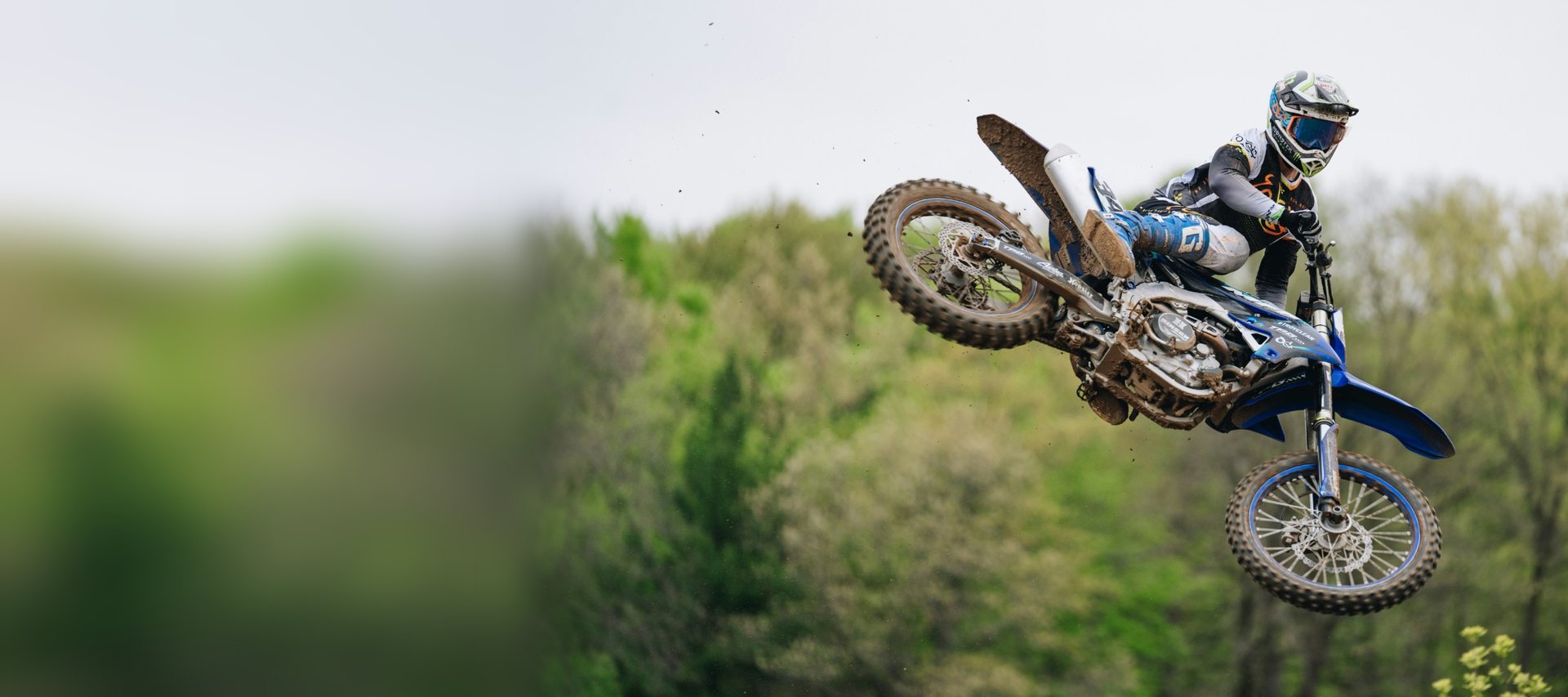 Motocross rider whipping a blue Yamaha dirt bike through the air over a jump