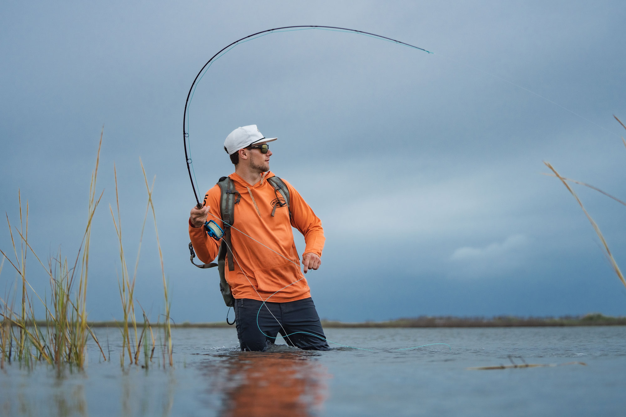 Man Casting a fly rod while wading in water