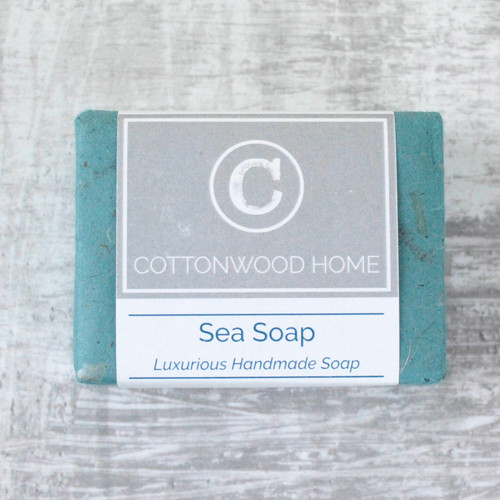 A bar of sea soap, wrapped in turquoise tissue with a printed branding and info band.