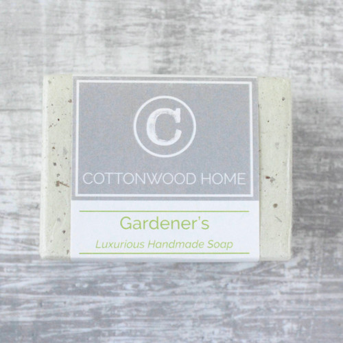 A bar of gardeners soap wrapped in natural tissue with a printed branding and info band.