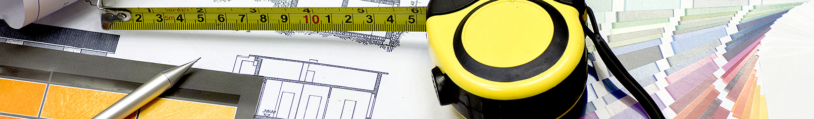 Measuring tape sitting on top of blueprints and color swatches