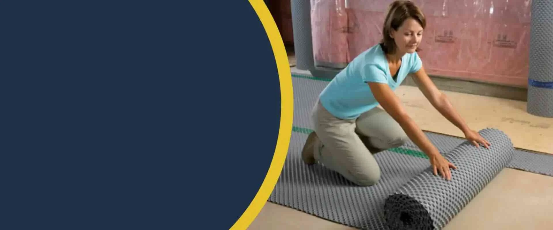 Installer rolling out a dimpled subfloor membrane over a basement floor