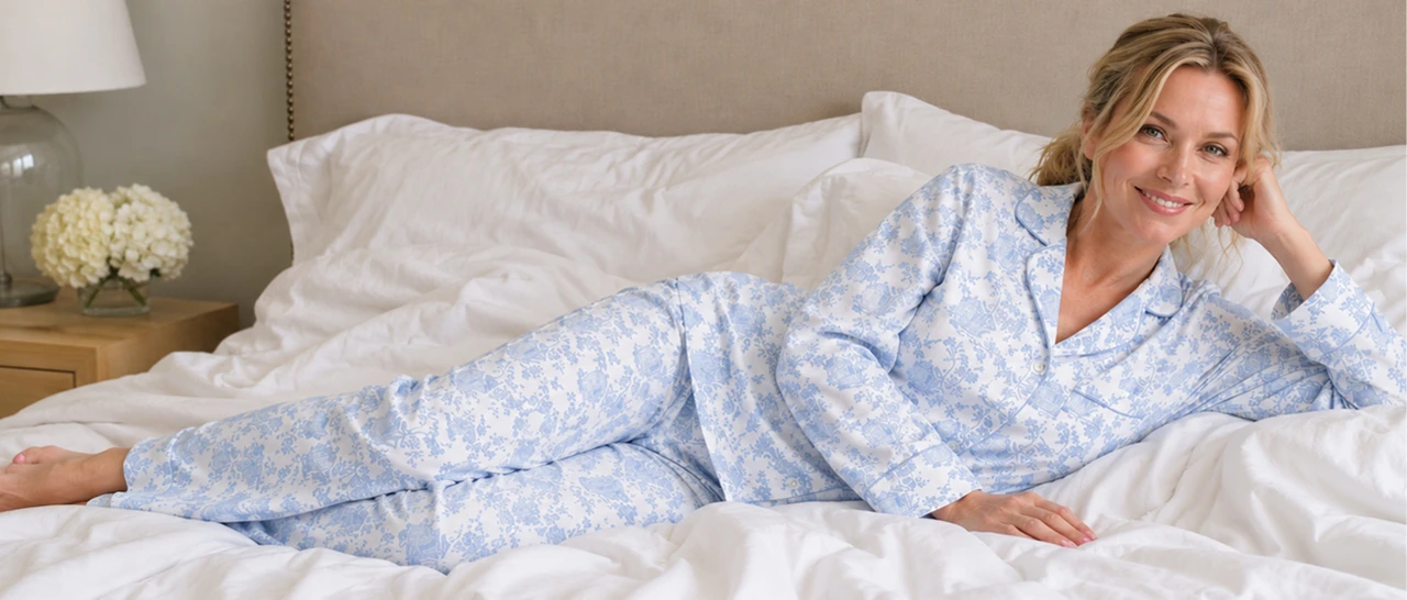 Woman relaxing across bed wearing Blue  and White toile pajamas