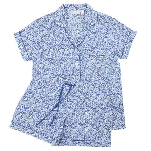 Women's cotton poplin button-down short sleeve pajama with shorts.  Printed with small-scale blue and white floral pattern trimmed with navy piping. Two-piece pajama set lying flat.