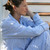 Woman sitting outside wearing traditional blue and white striped cotton seersucker long sleeve pajamas.