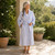 Woman wearing blue and white striped cotton seersucker wrap robe while standing outdoors 