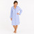 Woman wearing cotton button-down blue and white striped seersucker long sleeve nightshirt with navy piping.