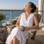 White cotton cambric nightgown with ruffle being worn by woman relaxing in chair overlooking water.