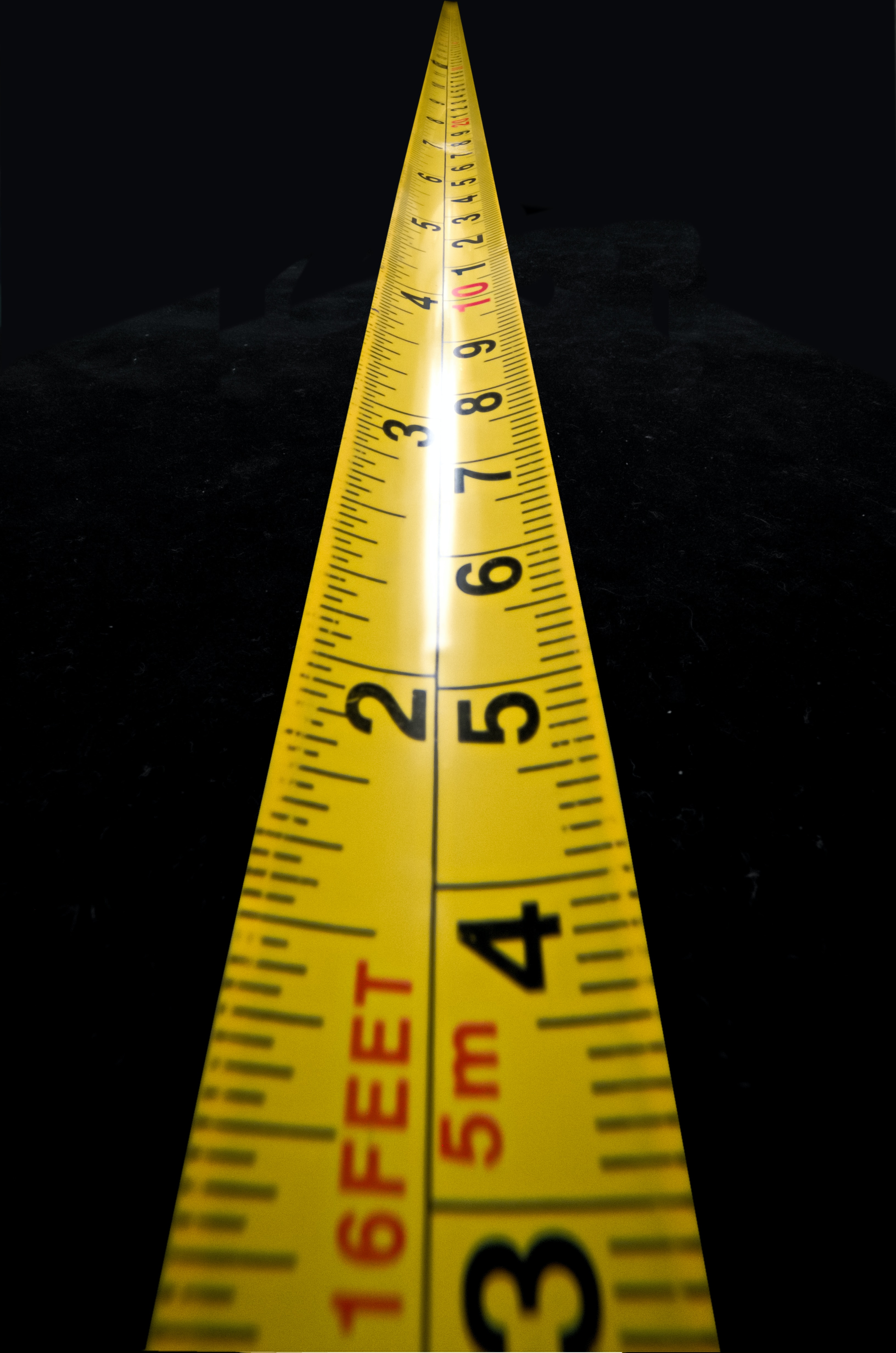 A tape measure stretching out into a black backdrop