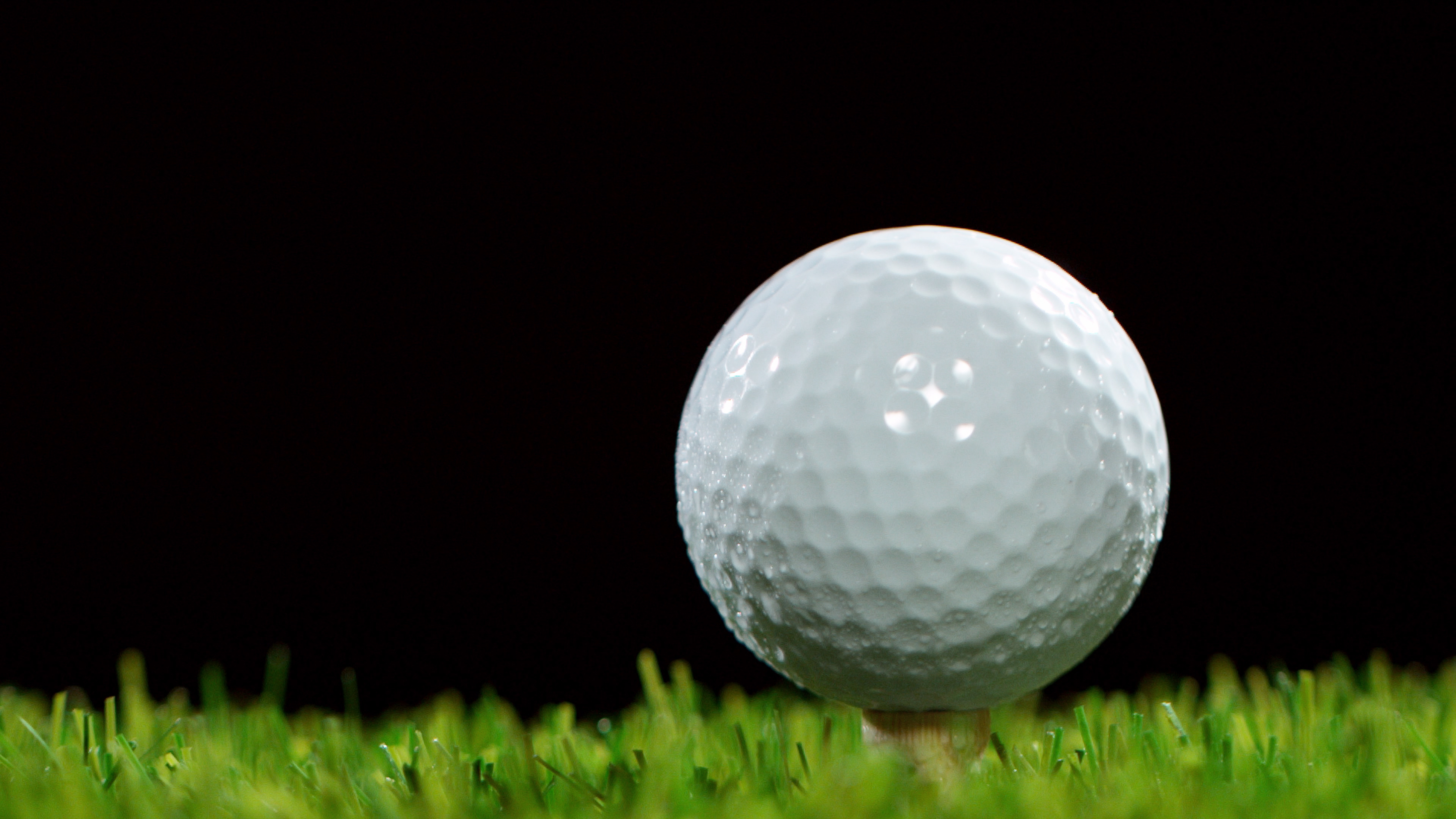 A golf ball on a tee set against black backdrop